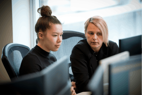 Two female members of the Rapid Global team review their work on a computer monitor
